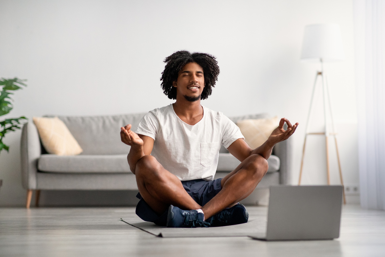 Online Yoga. Calm Black Guy Meditating with Laptop at Home